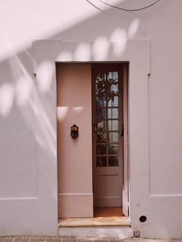 Light pink door with glass panels against a white wall in soft natural light.