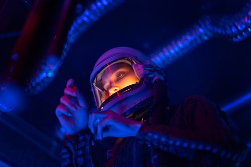 Free A spacewoman wearing a helmet, illuminated by futuristic neon lights, in an exploration setting. Stock Photo
