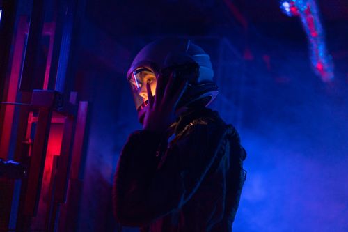 Free A female astronaut in a spacesuit explores a vividly lit, futuristic space setting. Stock Photo
