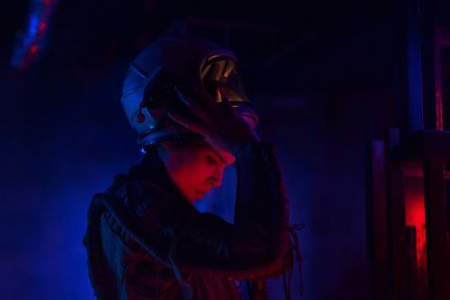 Free A woman wearing a space helmet in a dark, futuristic setting, preparing for space exploration. Stock Photo