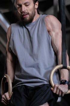 A male athlete performing strength exercises on gymnastic rings indoors.