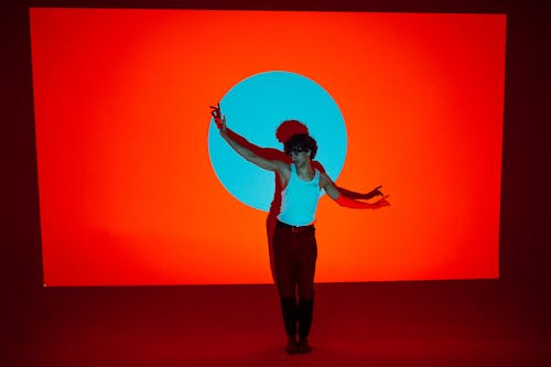 Free Man Standing In A Dancing Position Beside An Orange Wall Stock Photo