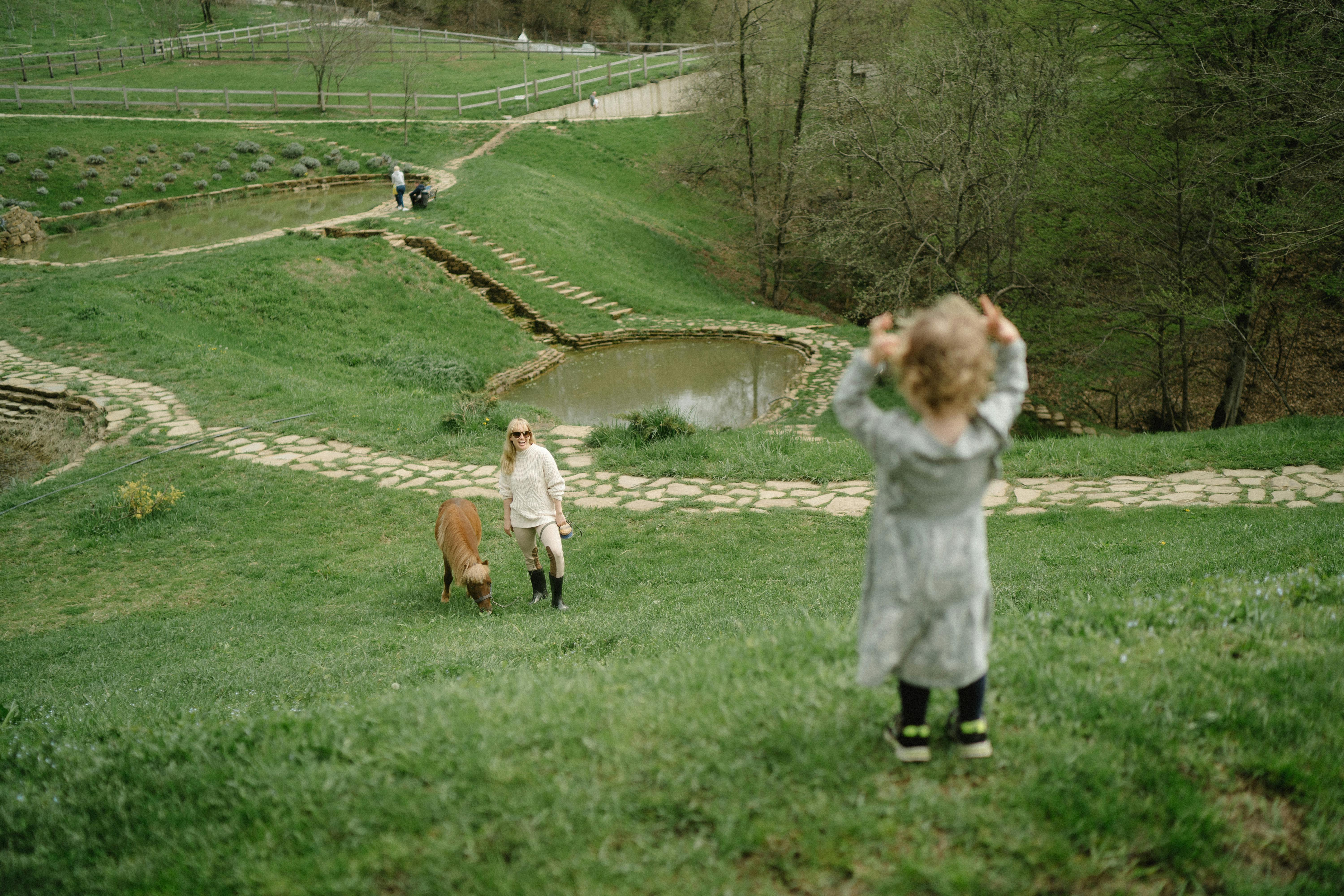 a mother and a child in a farm with a pony