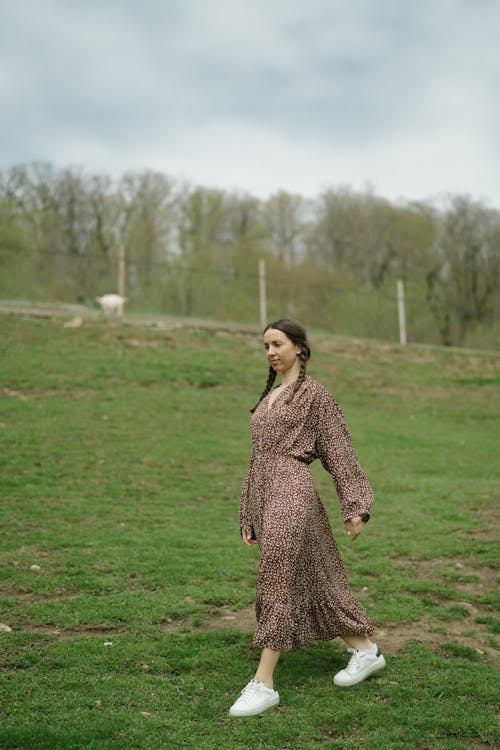 Woman in Printed Dress Walking on Grassland