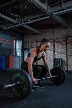 A determined woman lifts a barbell during a weightlifting session in a gym.