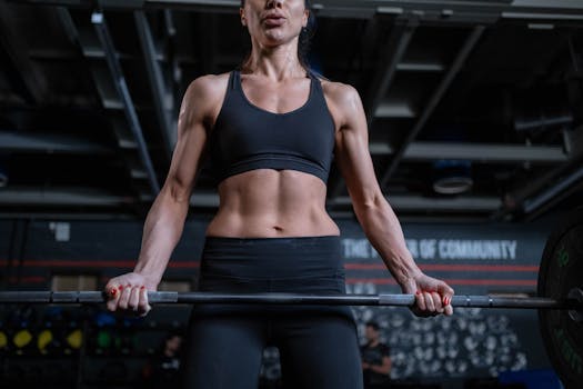 Strong woman lifting barbell in gym. Focus on fitness, strength, and healthy living.