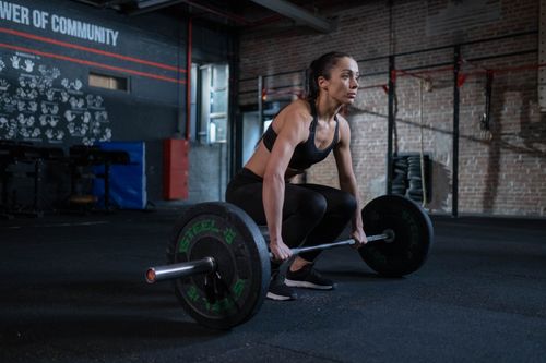 Free A determined woman prepares to lift barbell in a gym, showcasing strength and focus. Stock Photo