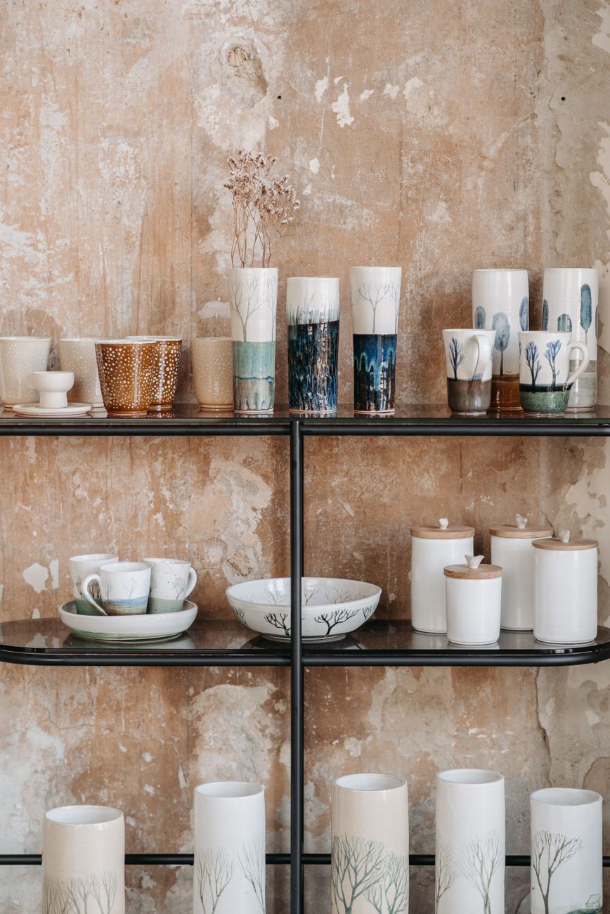 Collection of handmade ceramic vases and containers on rustic shelves, showcasing artistic craftsmanship.