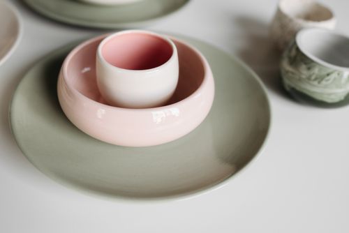 Free A close-up of colorful ceramic bowls and cups on a white table. Stock Photo