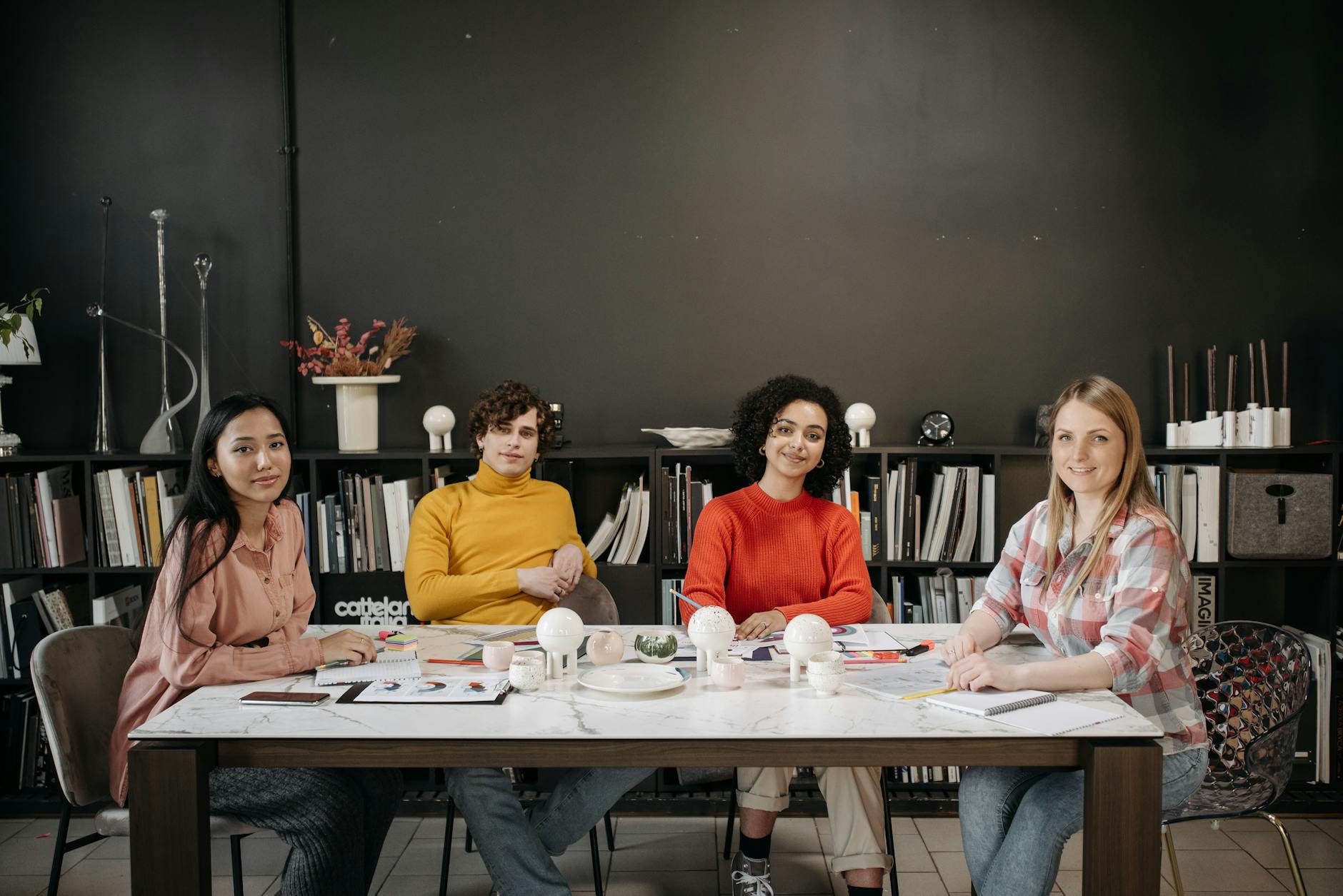 A diverse team of young adults working together in a creative office space, discussing and collaborating on projects.