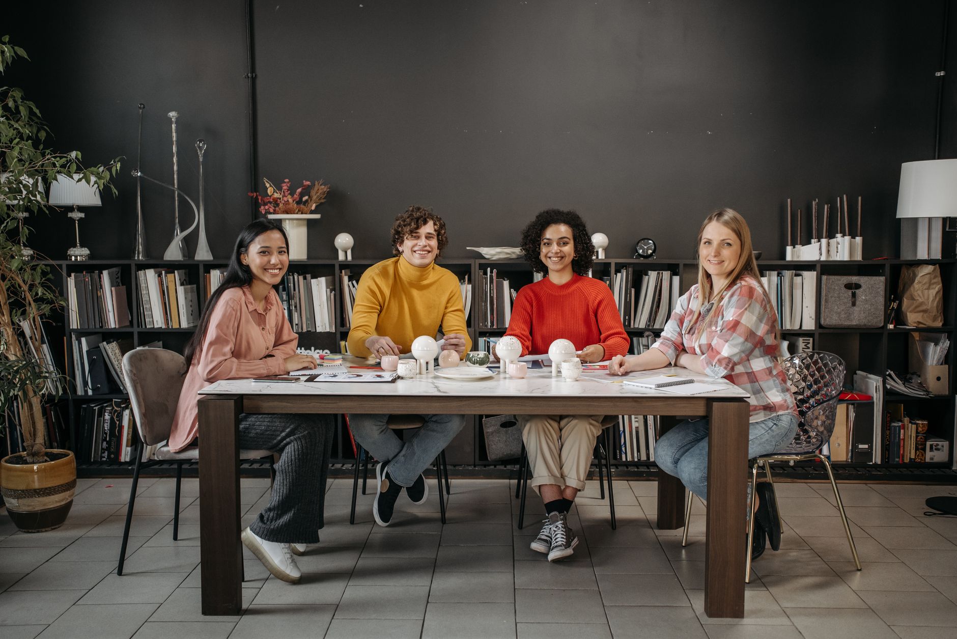 Four diverse professionals collaborating around a table in a modern office setting.