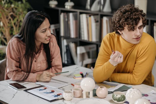 Asian woman and caucasian man in a creative office meeting discussing business strategy.