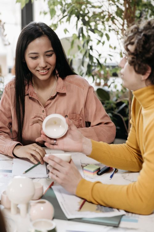 Free Two colleagues review ceramic products during a creative meeting indoors. Stock Photo