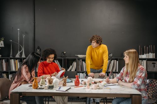 Free A diverse group in an office setting brainstorming with ceramic products on a table. Stock Photo