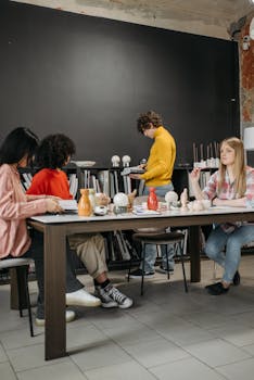 A diverse group of adults in a creative meeting discussing ceramics in a modern office.