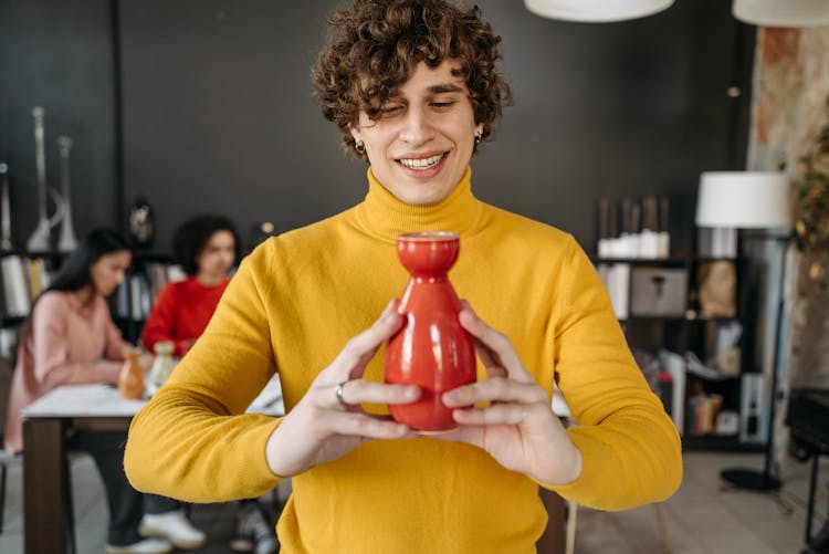 A Man In Yellow Sweater Holding Ceramic Object