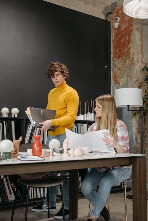 Free Young professionals collaborating in a modern office setting, reviewing design concepts at a table. Stock Photo