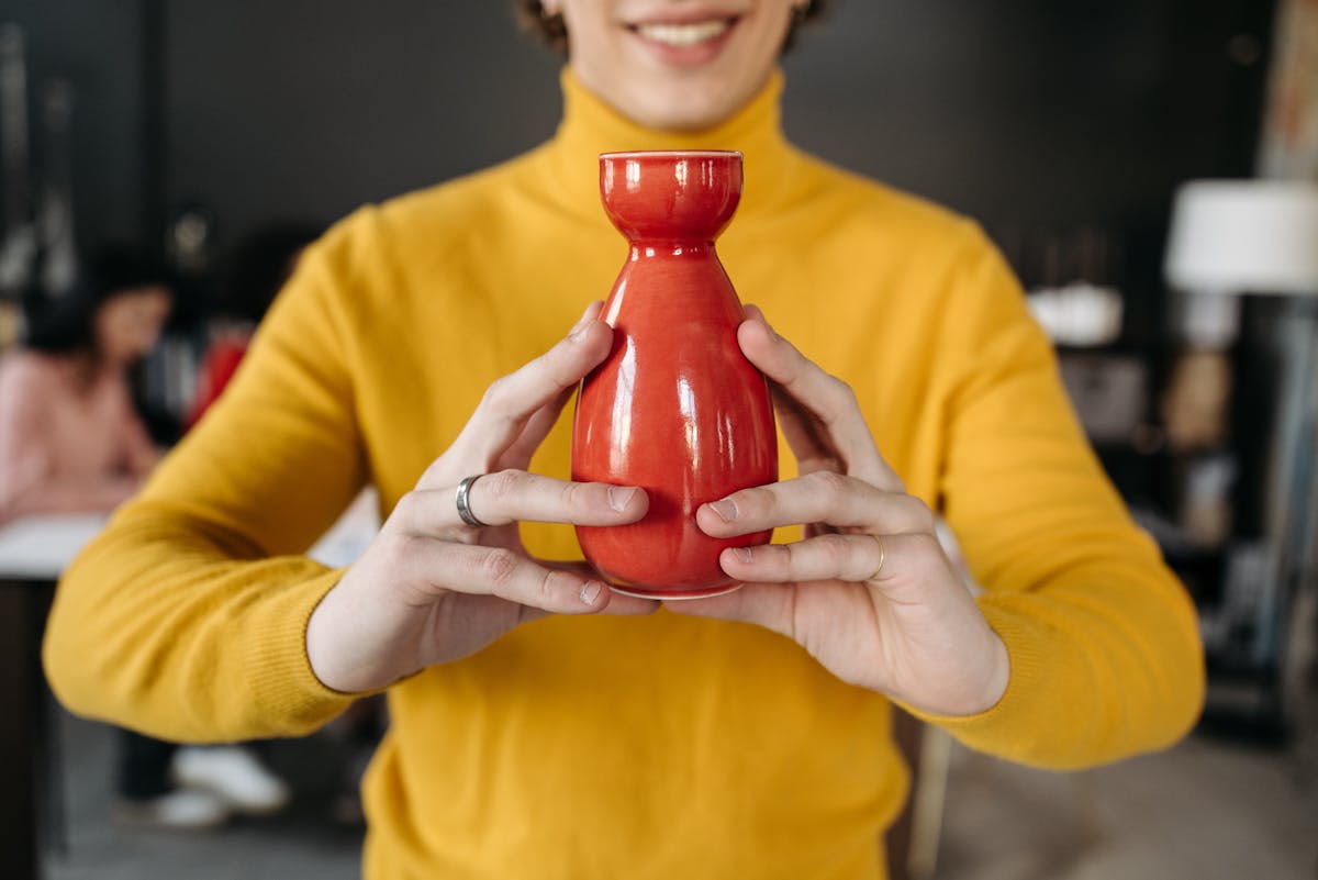 Close-Up Shot of a Person Holding a Ceramic Bottle