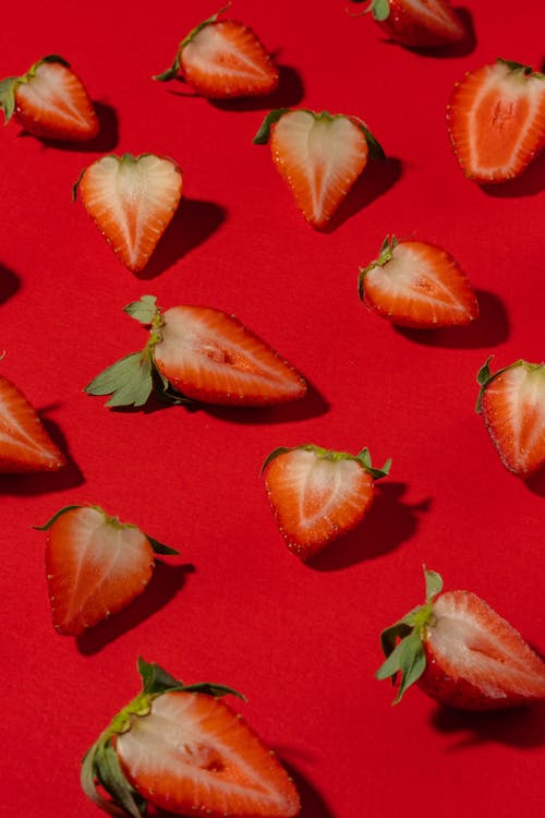 Strawberries Cut in Half over Red Surface