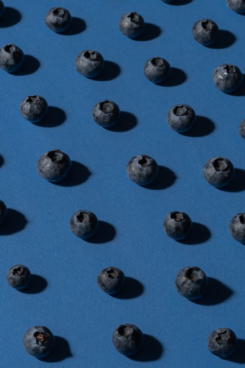 Free Scattered fresh blueberries on a blue backdrop, offering a minimalist food composition. Stock Photo