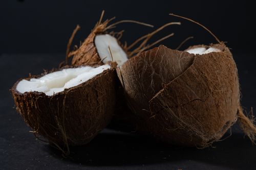 Free A moody still life of open coconut halves showcasing their fresh white flesh against a dark backdrop. Stock Photo