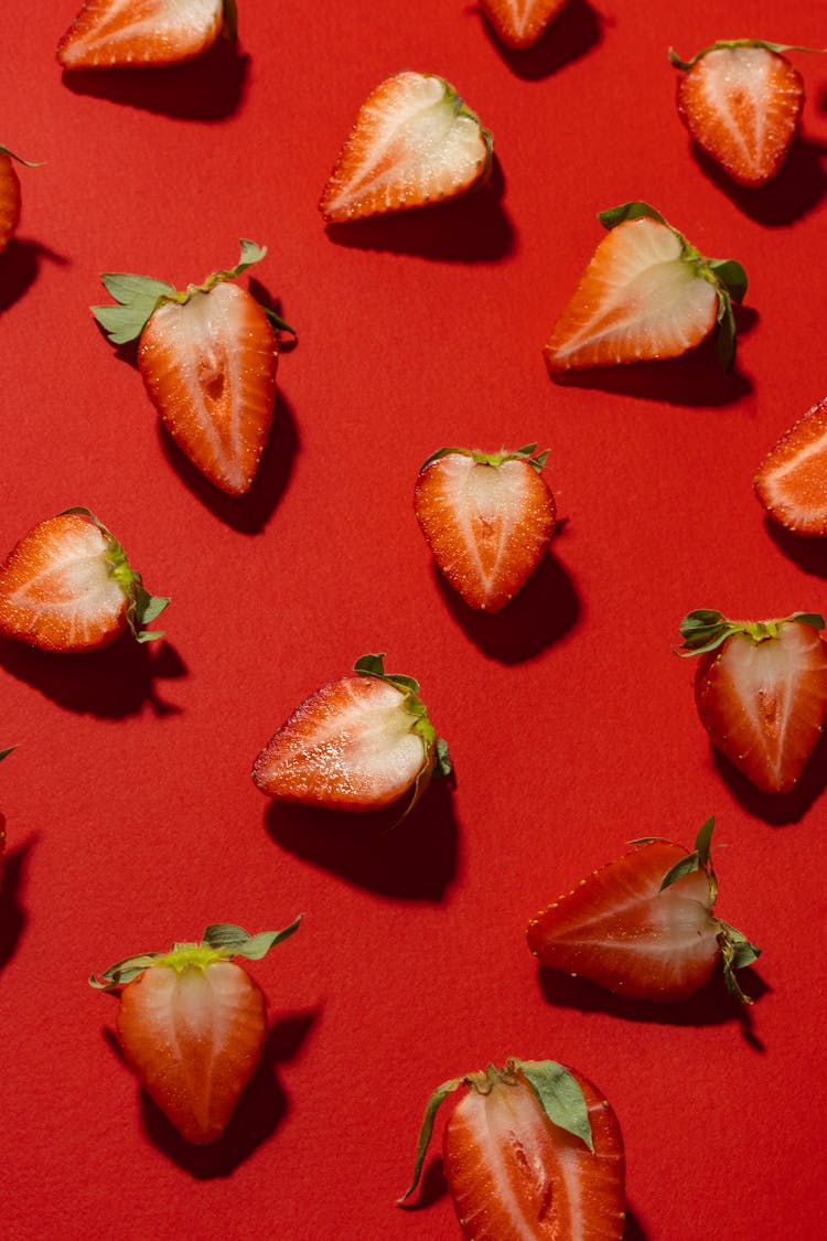 Photo Of Sliced Strawberries On Red Surface