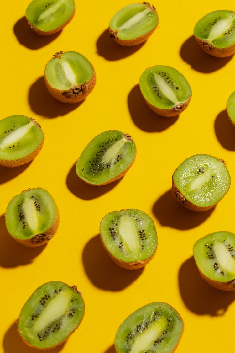 Close-Up Photo Of Sliced Kiwis On Yellow Surface