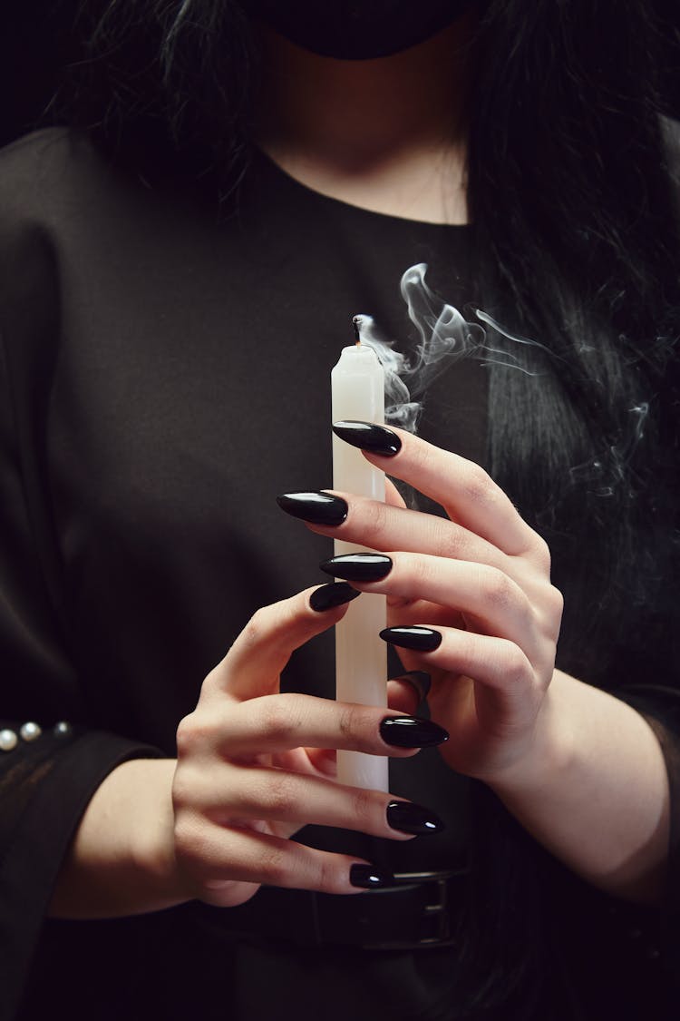 Person With Black Nail Polish Holding A White Candle