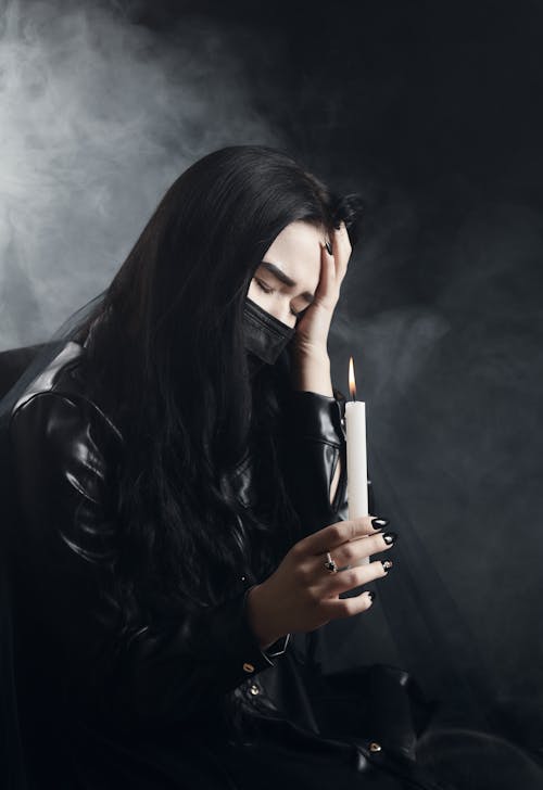 Woman in Black Leather Jacket Holding a Lighted Candle