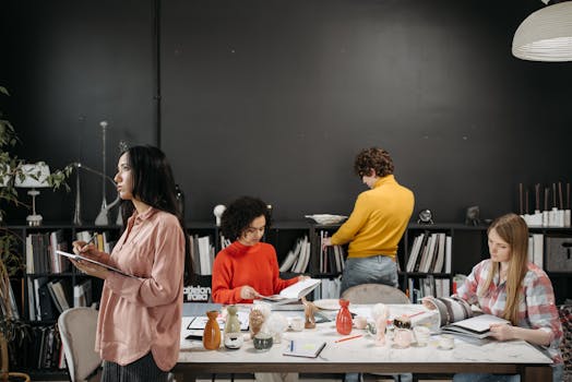 A group of adults engaged in creative work and discussion around a table in an office setting.