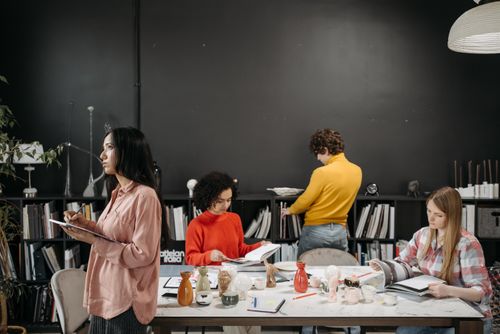 Free A group of adults engaged in creative work and discussion around a table in an office setting. Stock Photo