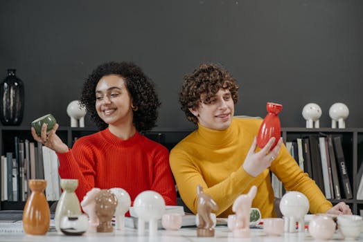 Two young adults displaying modern ceramics in a creative workspace.