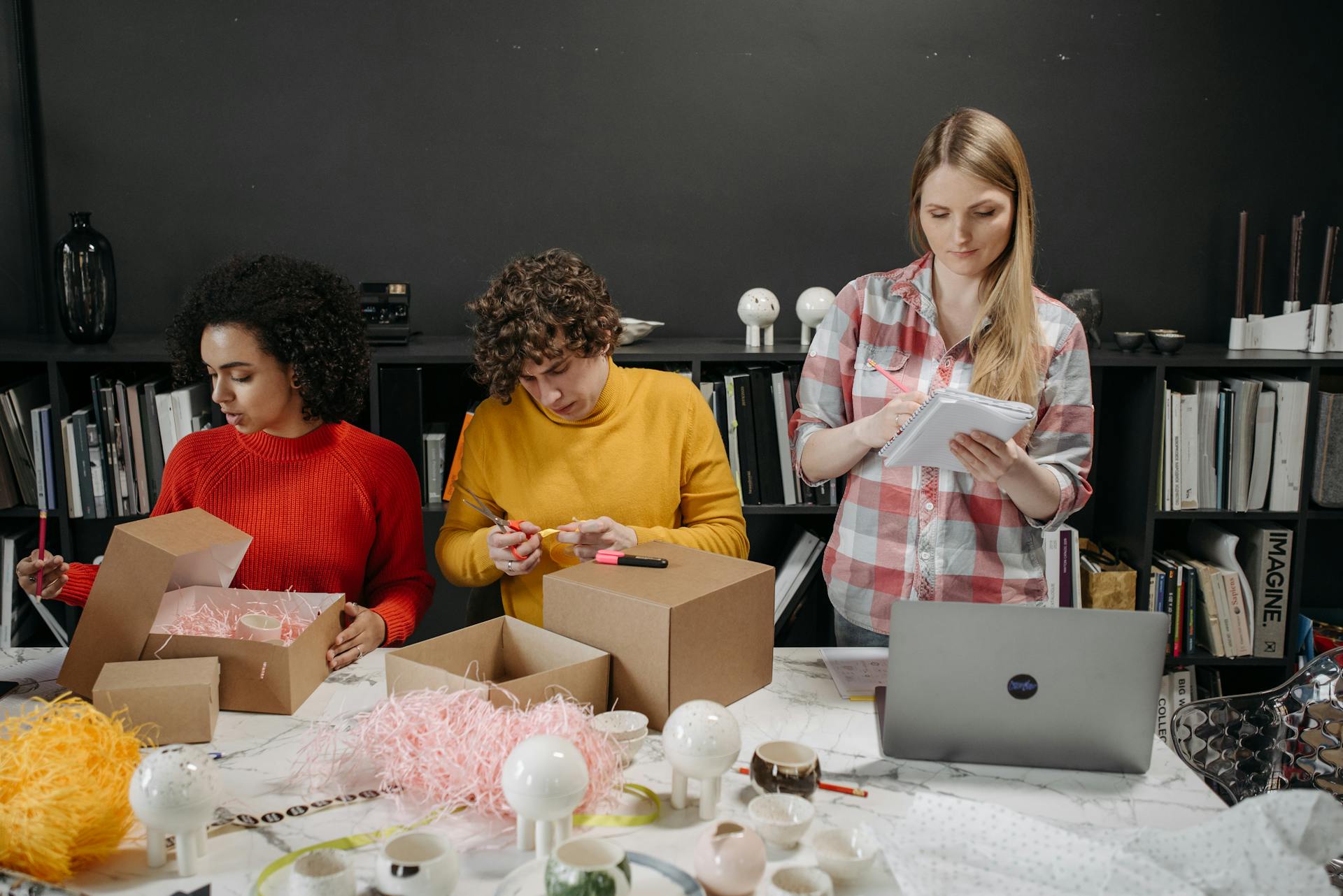 Diverse team working together, preparing packages in a creative office setting.