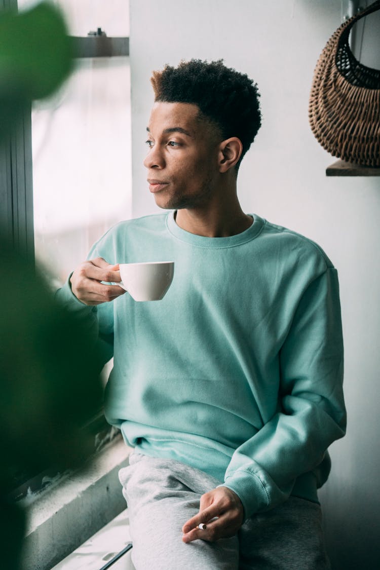 Thoughtful Black Man With Cigarette Drinking Coffee Near Window