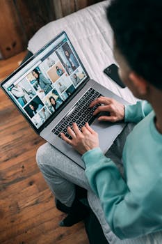A person using a laptop to browse photos while sitting in a bedroom environment.