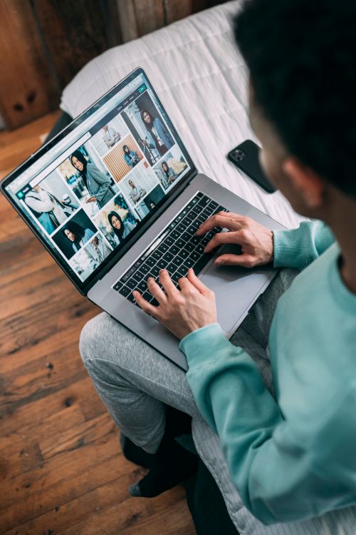 Free From above of crop unrecognizable African American male freelancer typing on modern netbook while sitting on bed during remote work Stock Photo