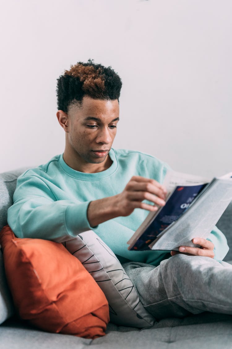 Black Man Reading Magazine On Sofa