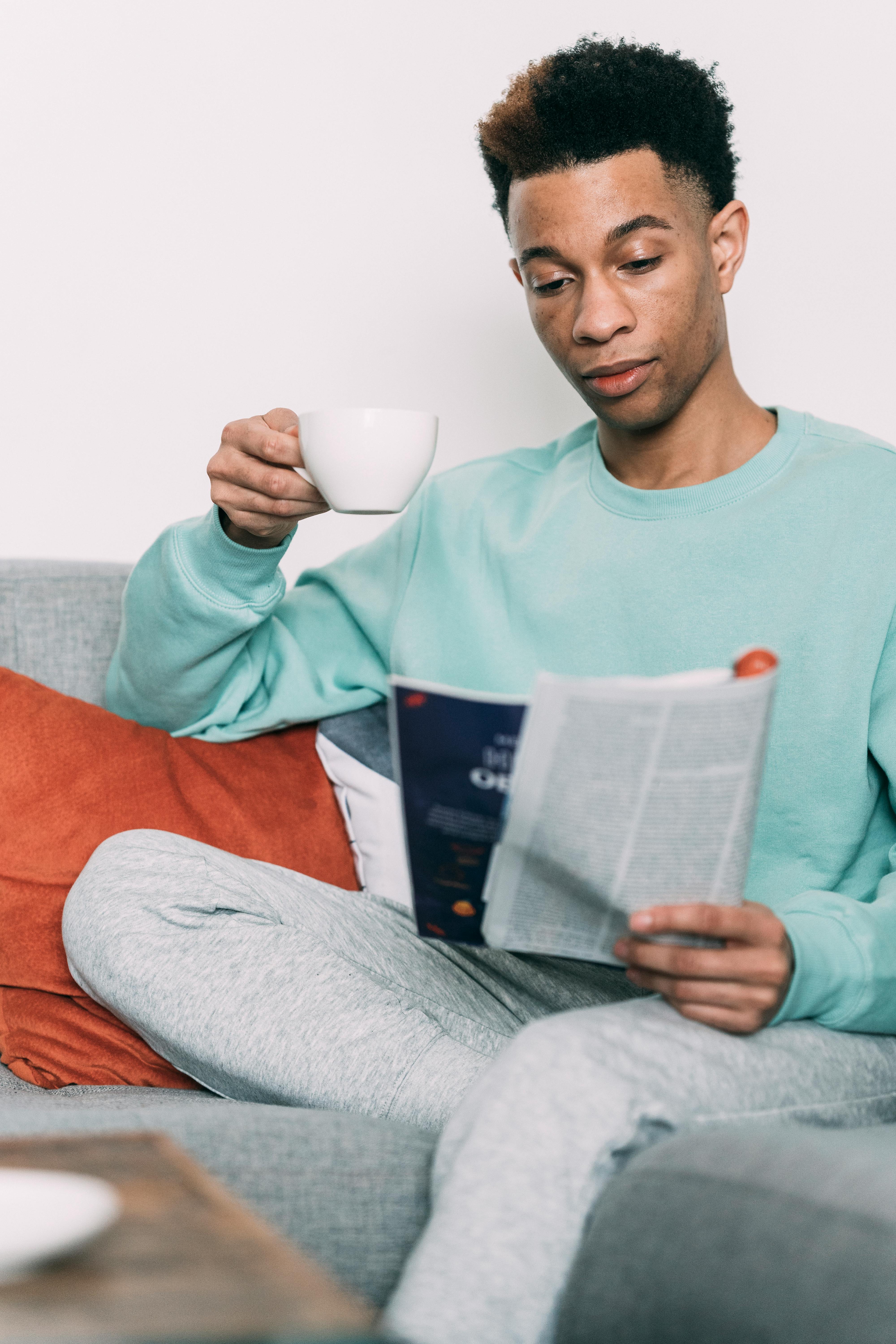 thoughtful black man with coffee reading magazine