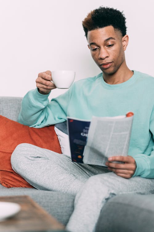 Free Thoughtful black man with coffee reading magazine Stock Photo