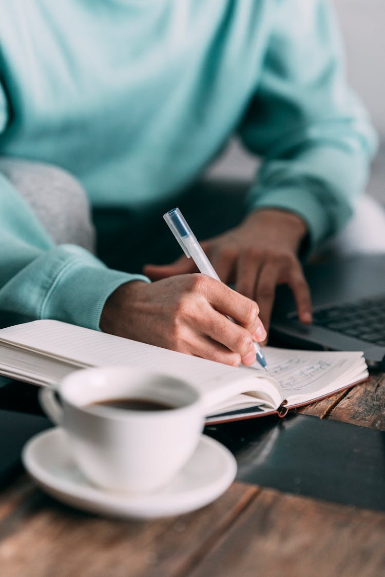 Unrecognizable Man Writing In Notepad