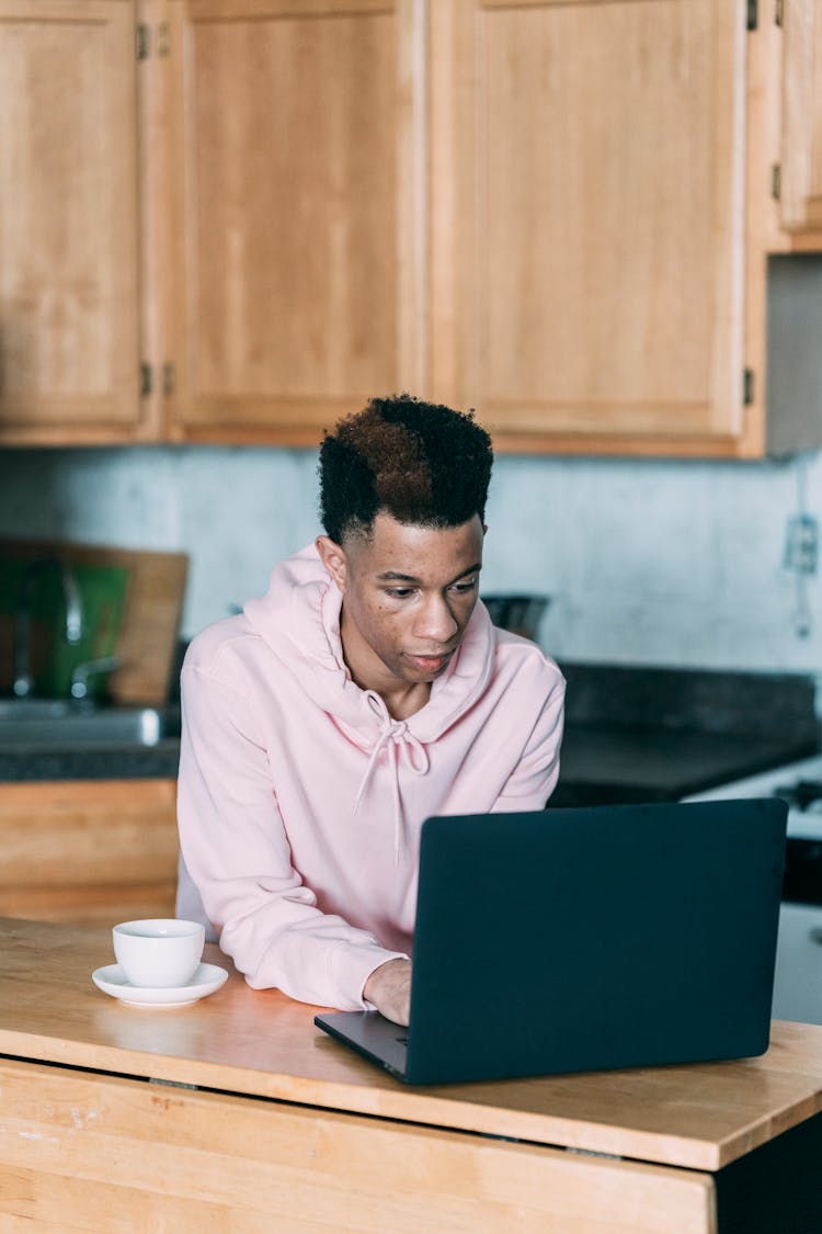 Black Man Using Laptop In Kitchen