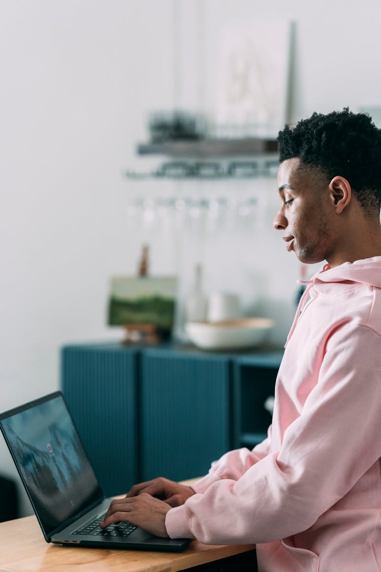 Black Man Typing On Laptop In Kitchen