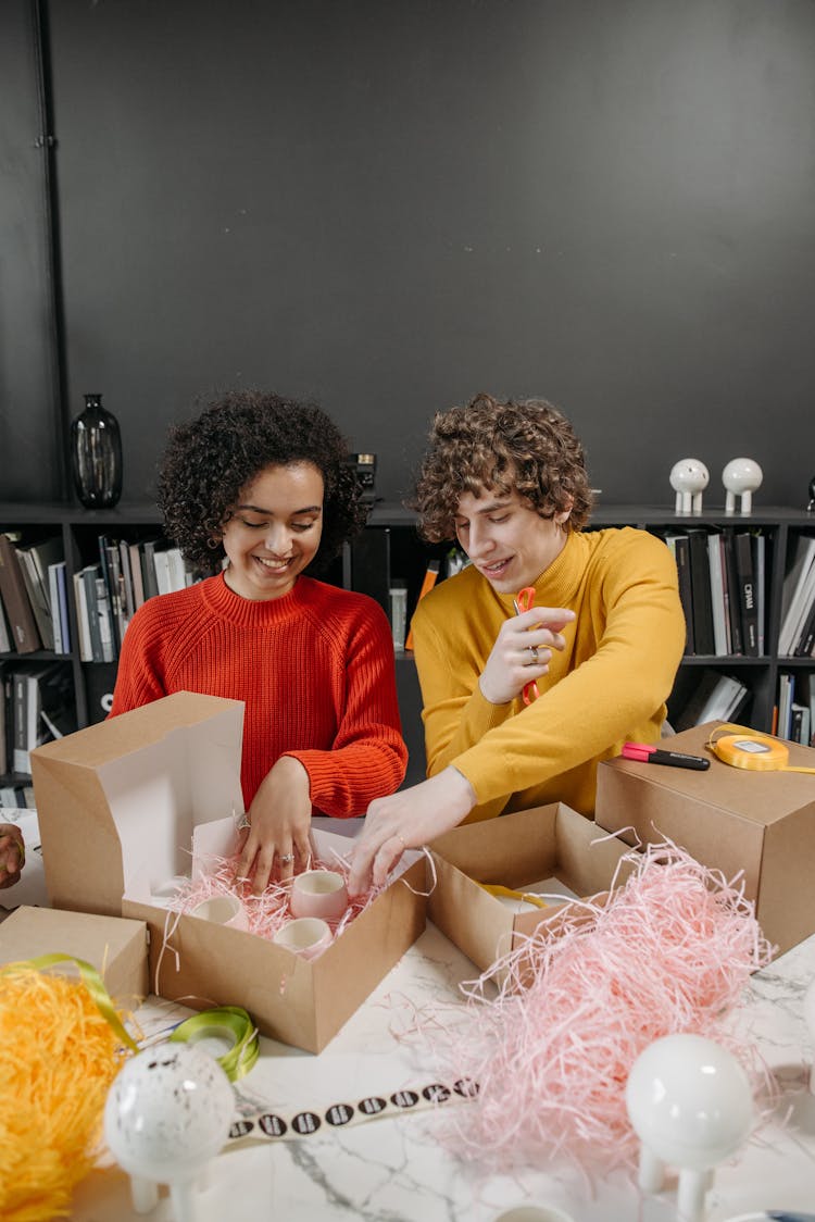 A Woman And Man Putting Ceramics In The Box