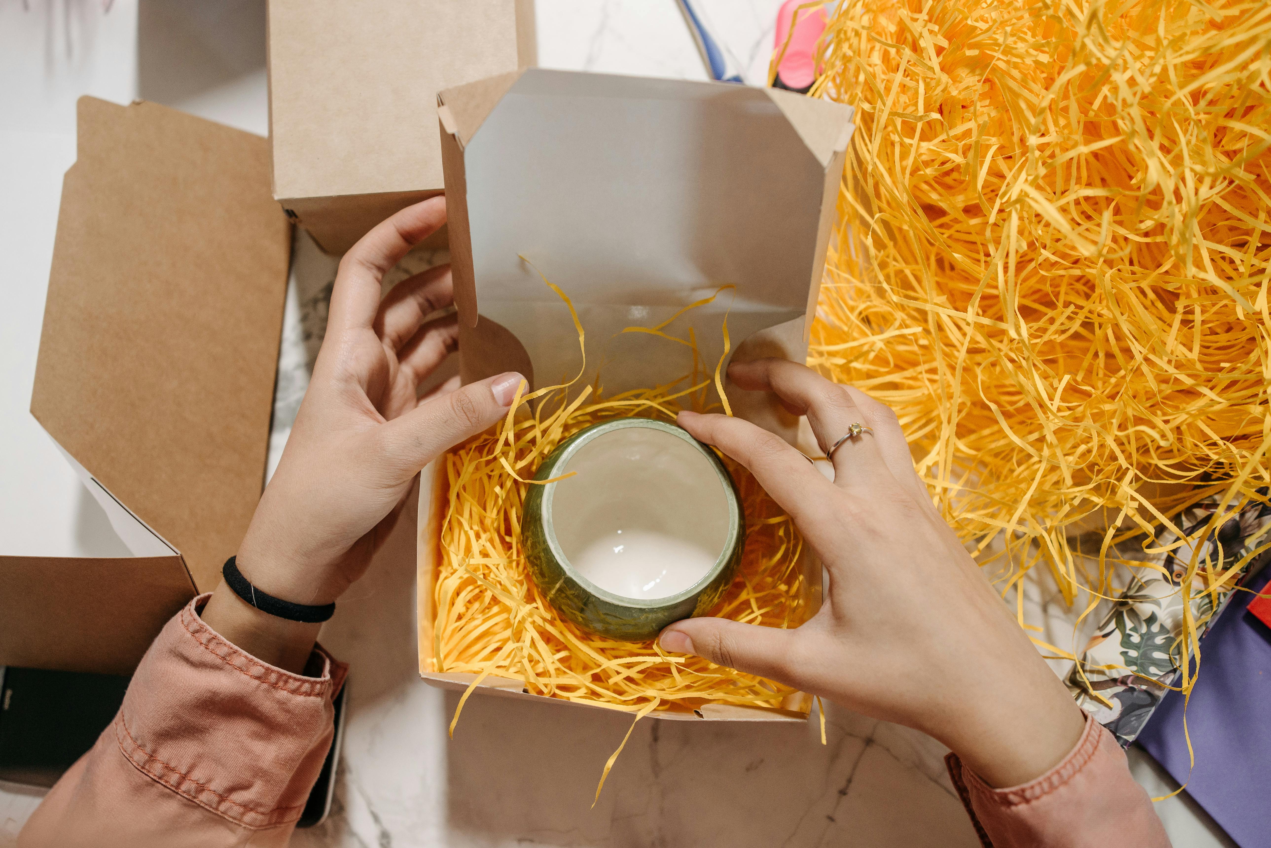 a person packing ceramic cup in a cardboard box