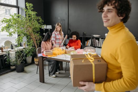 Team collaborating on gift packaging inside a modern workspace, emphasizing creativity and teamwork.