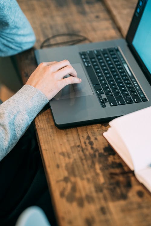 Person working with laptop at wooden table