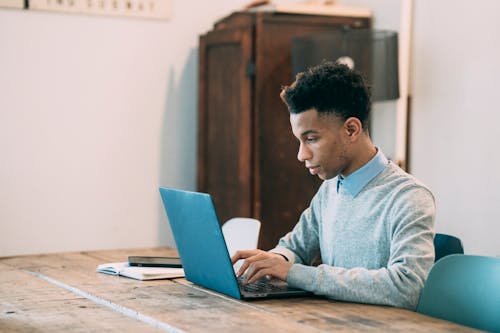 Free Black man typing project on laptop at table Stock Photo