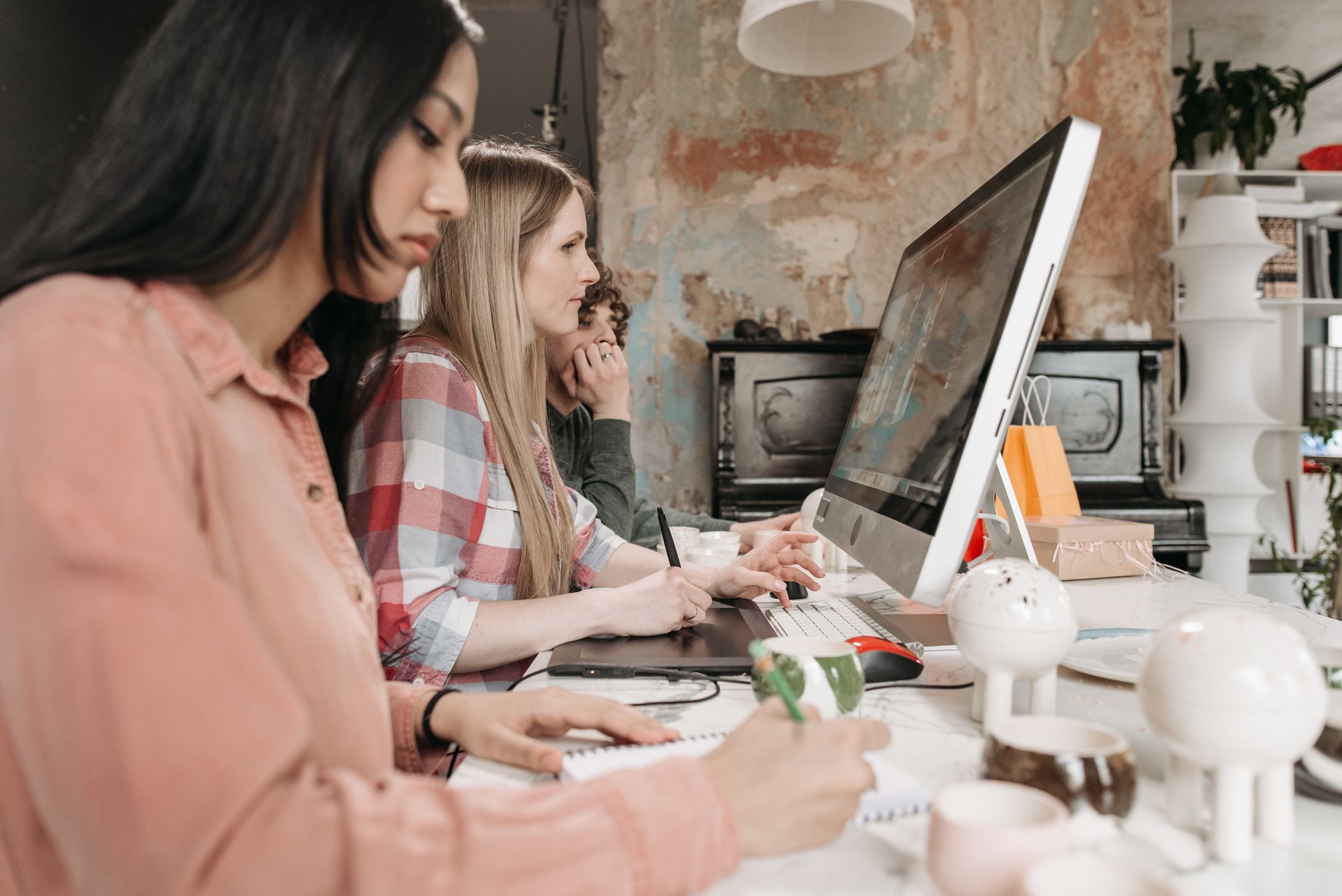 Three young professionals collaborate with technology in a stylish office setting, fostering creativity.