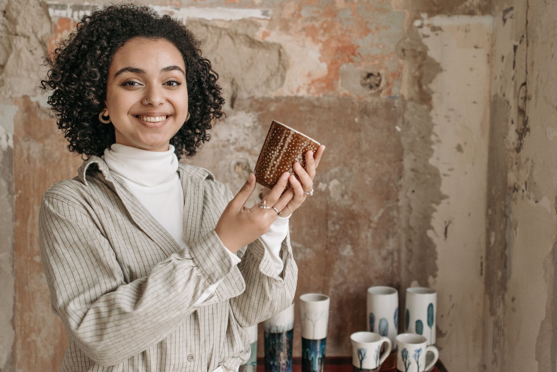Young Woman Holding a Handmade Ceramic Cup and Smiling