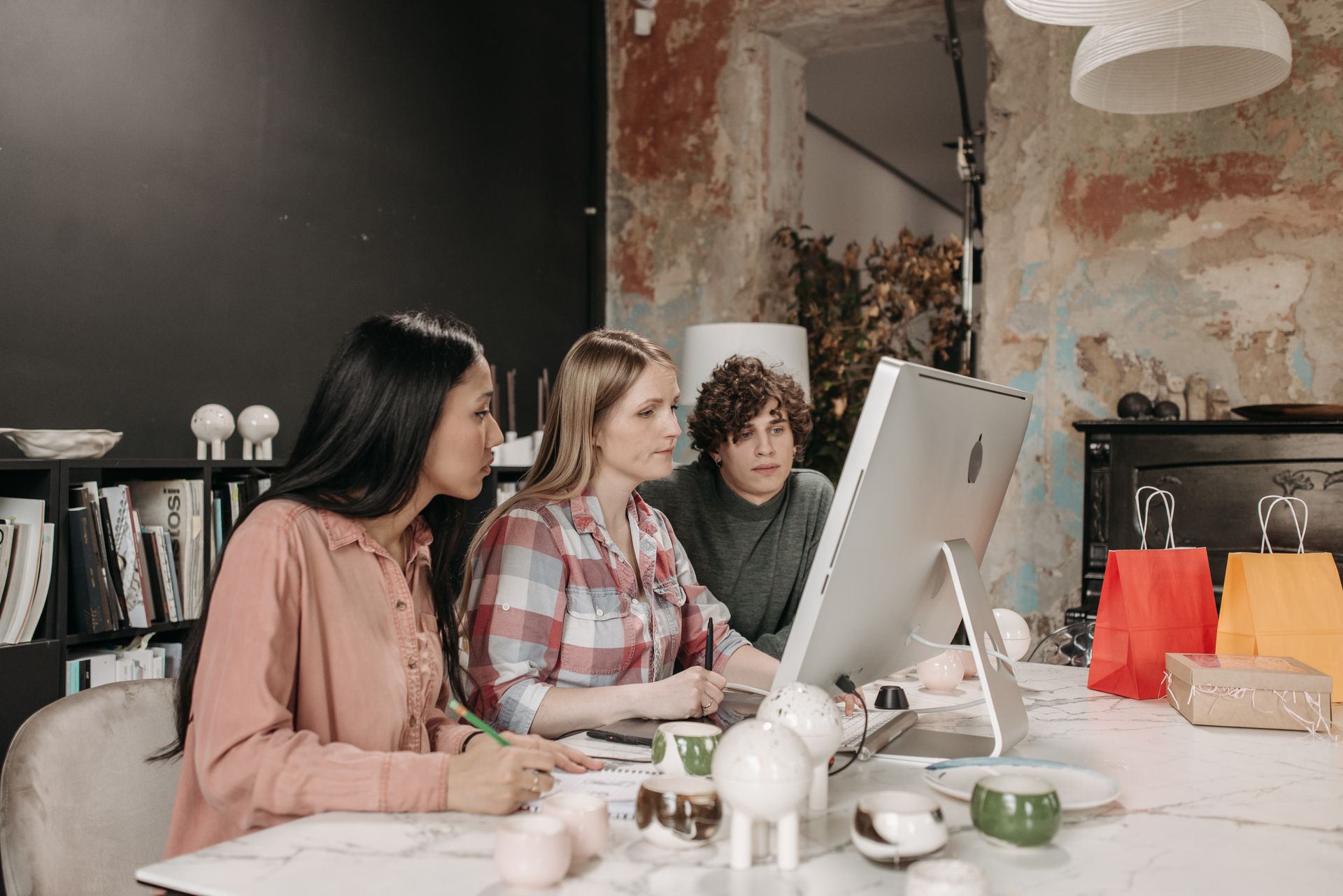 A diverse team of three adults working together on a computer in a modern office.
